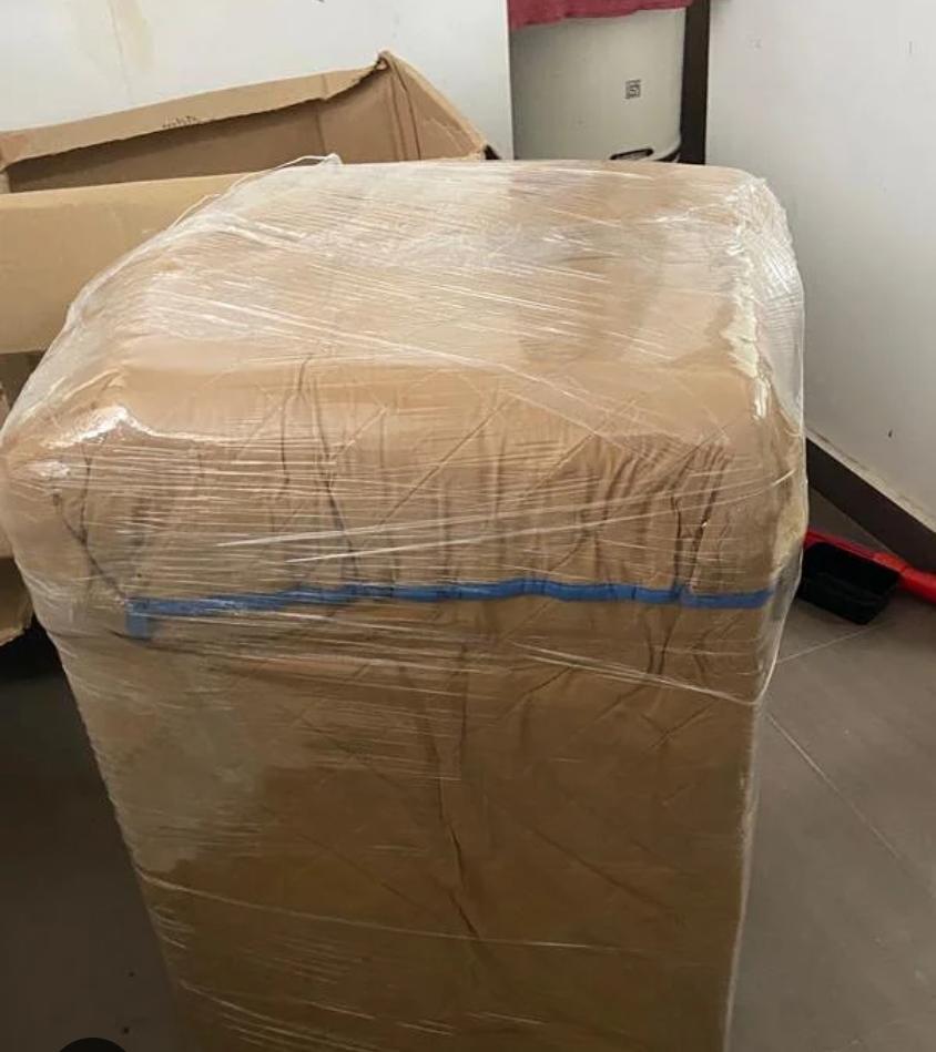 Large household item wrapped in brown paper and clear plastic stretch film for moving